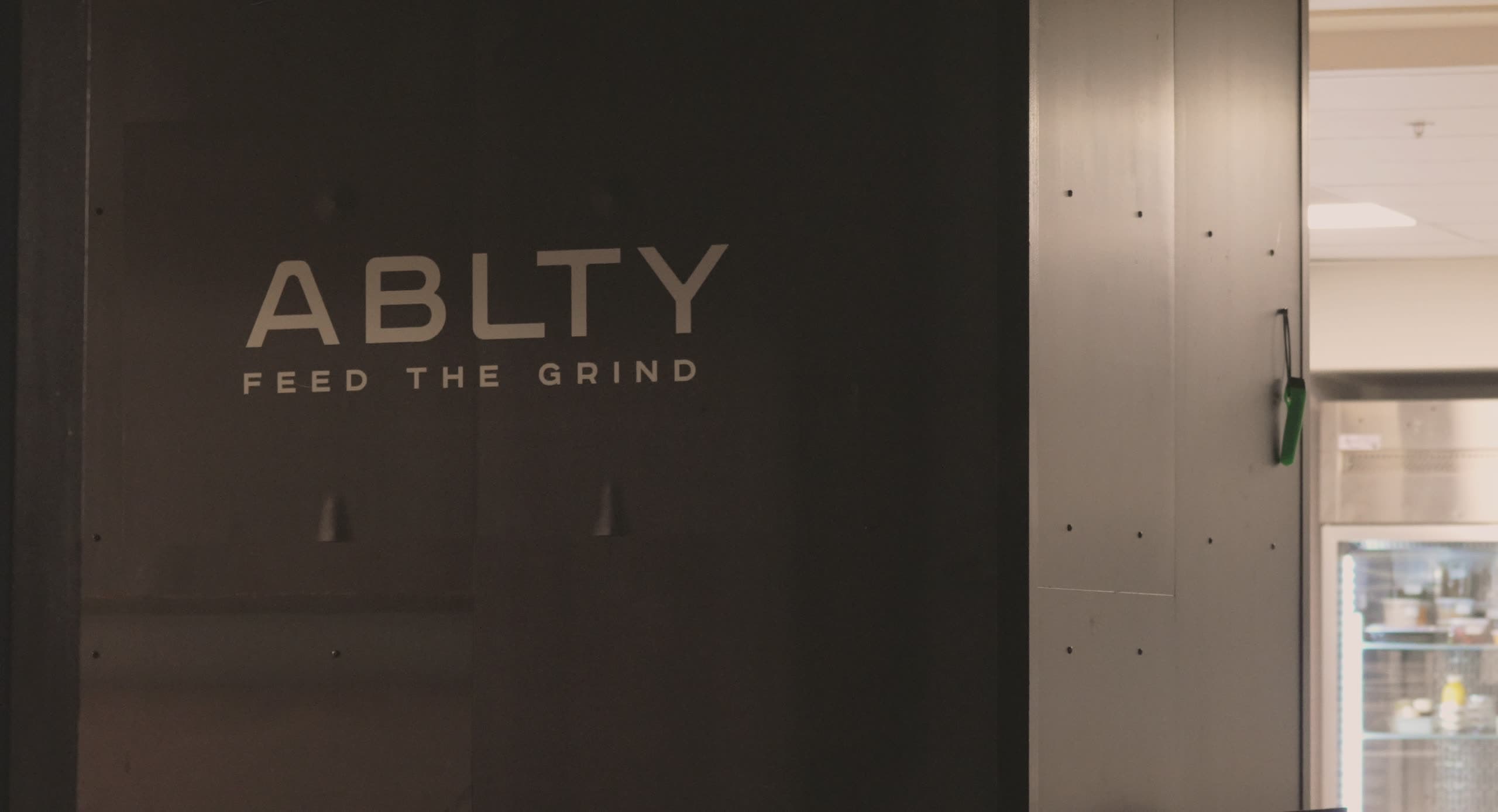 The ABLTY “Feed the Grind” wall mark inside the Dupont Circle commissary, beside the pass to the cold room