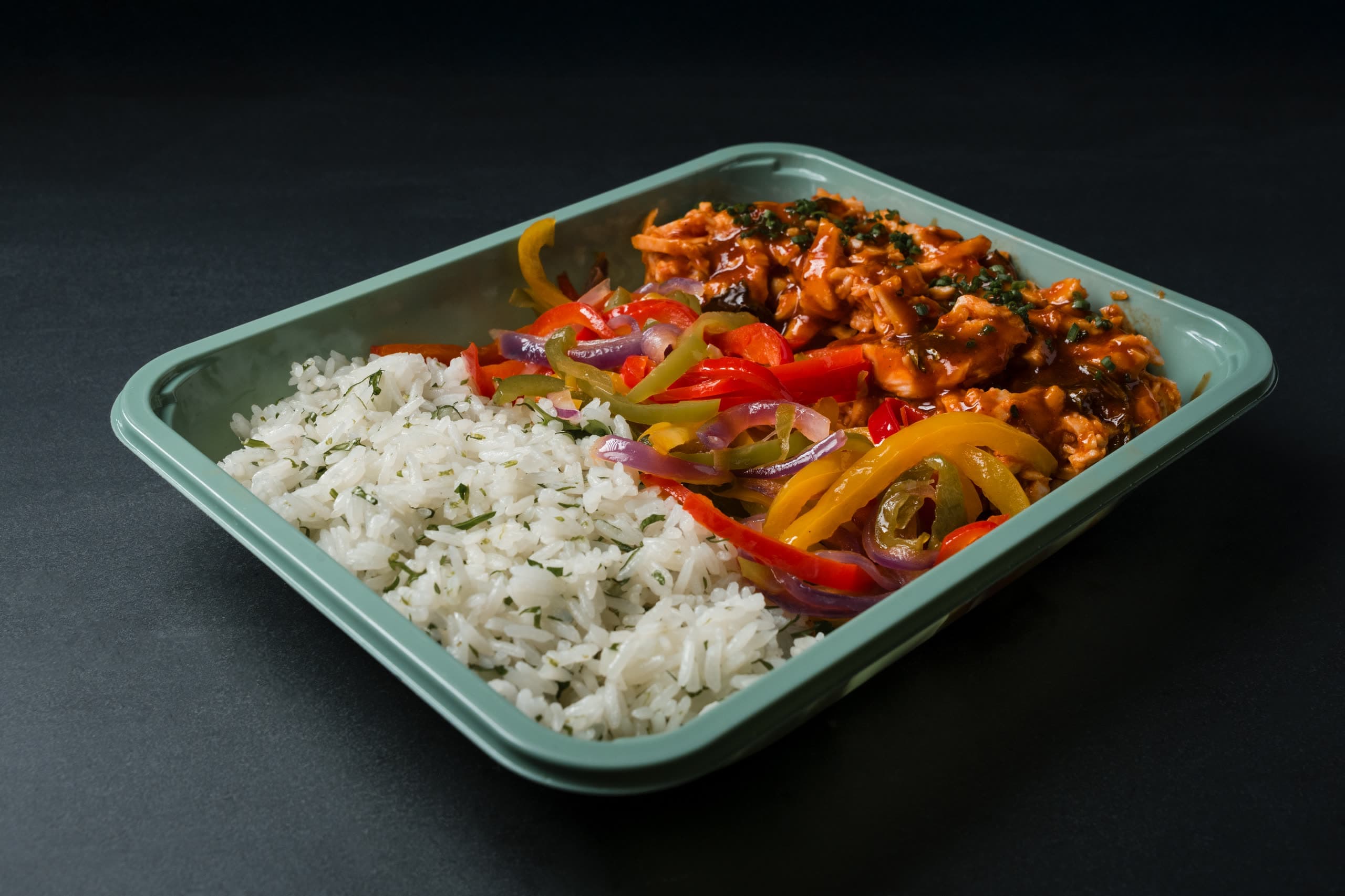 Glazed barbecue chicken with peppers and onions beside herbed rice in a sage-green ABLTY tray