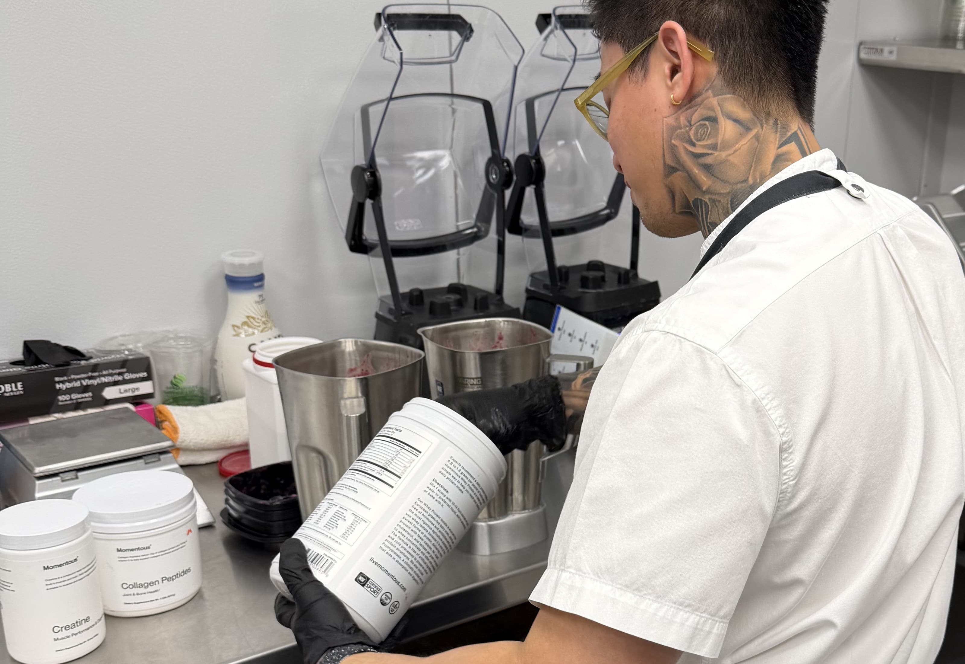 Chef at commercial kitchen prep station with blenders and equipment