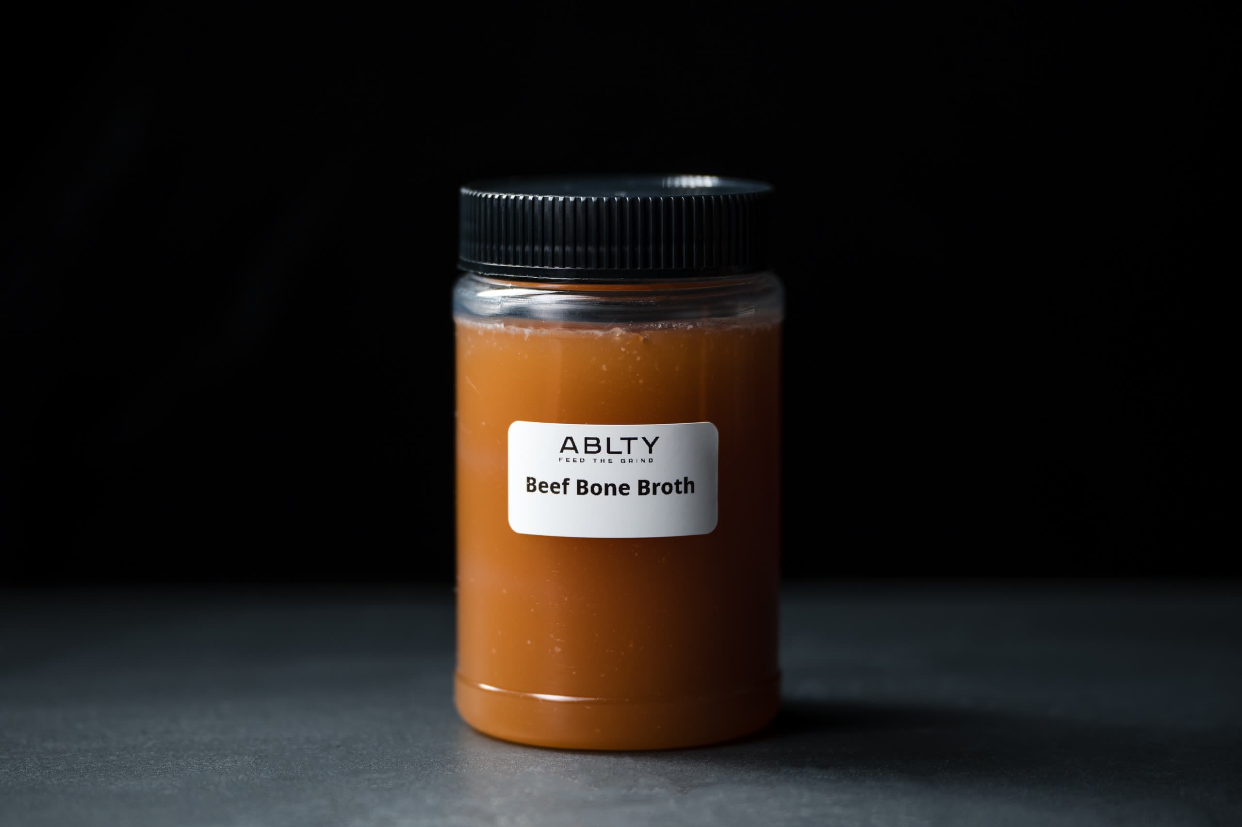 A sealed jar of ABLTY beef bone broth, labelled by the kitchen that made it