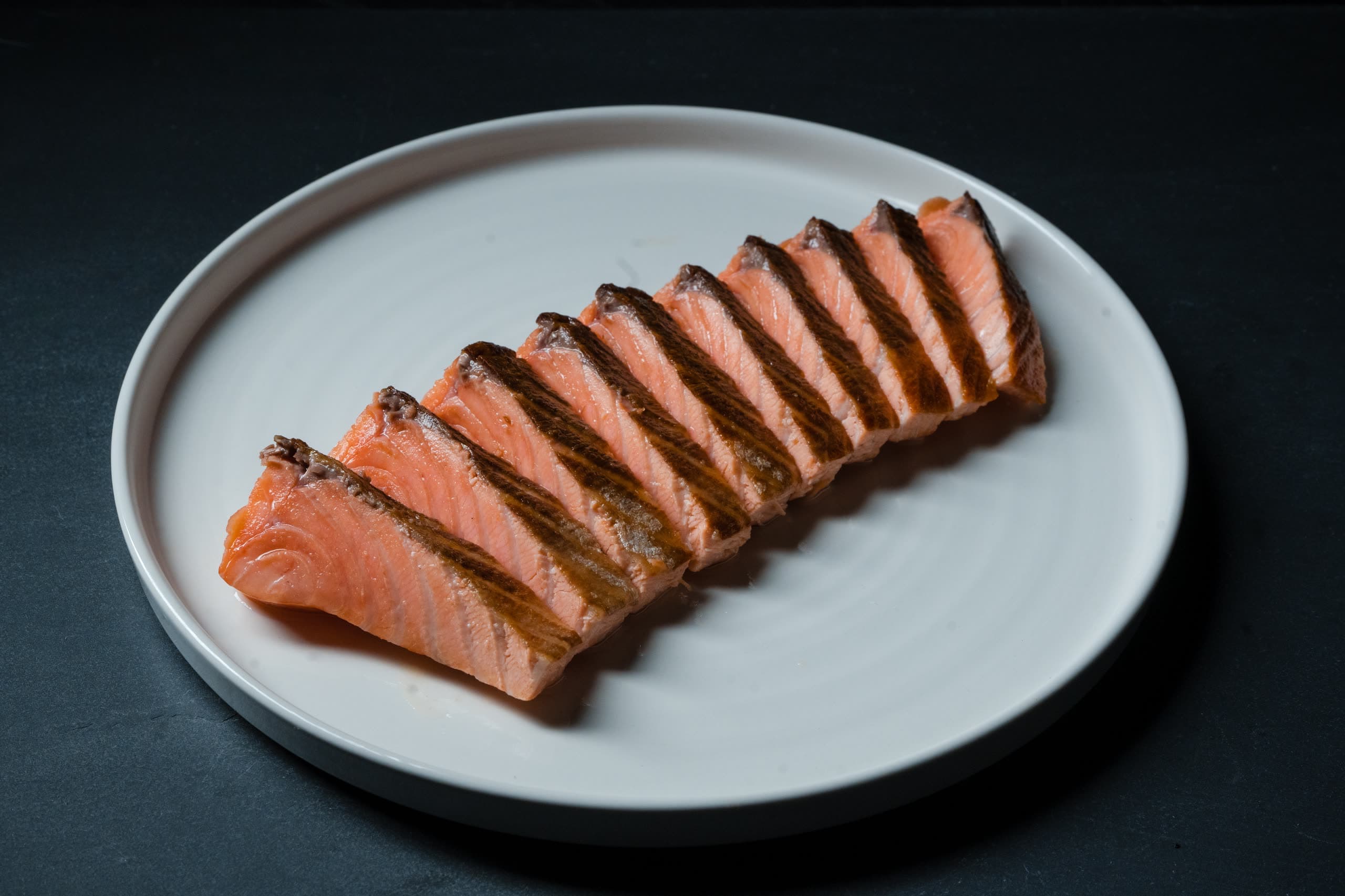 Slow-cooked salmon fillet, sliced and fanned across a white plate