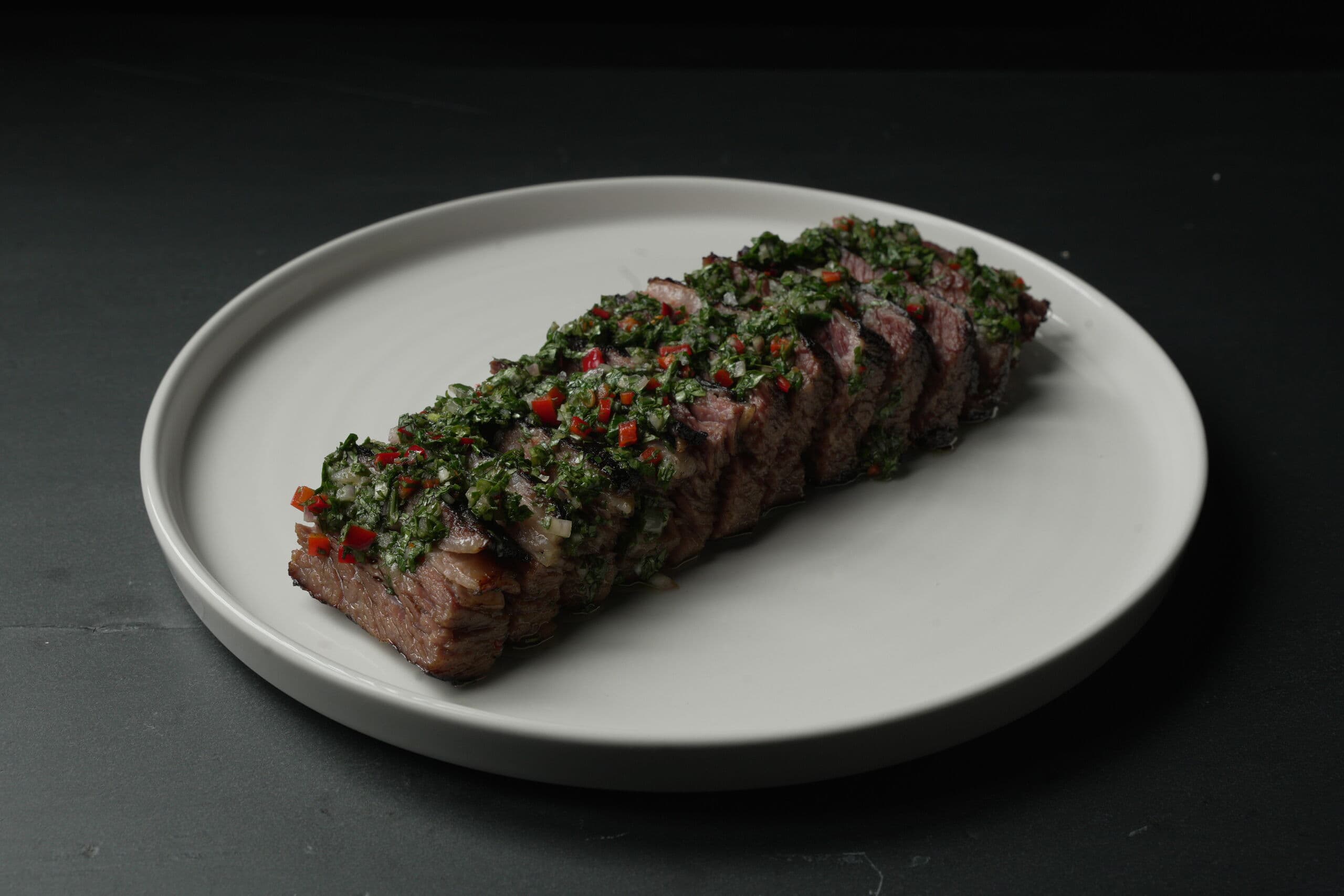 Sliced chimichurri steak plated in the ABLTY commissary for professional team service