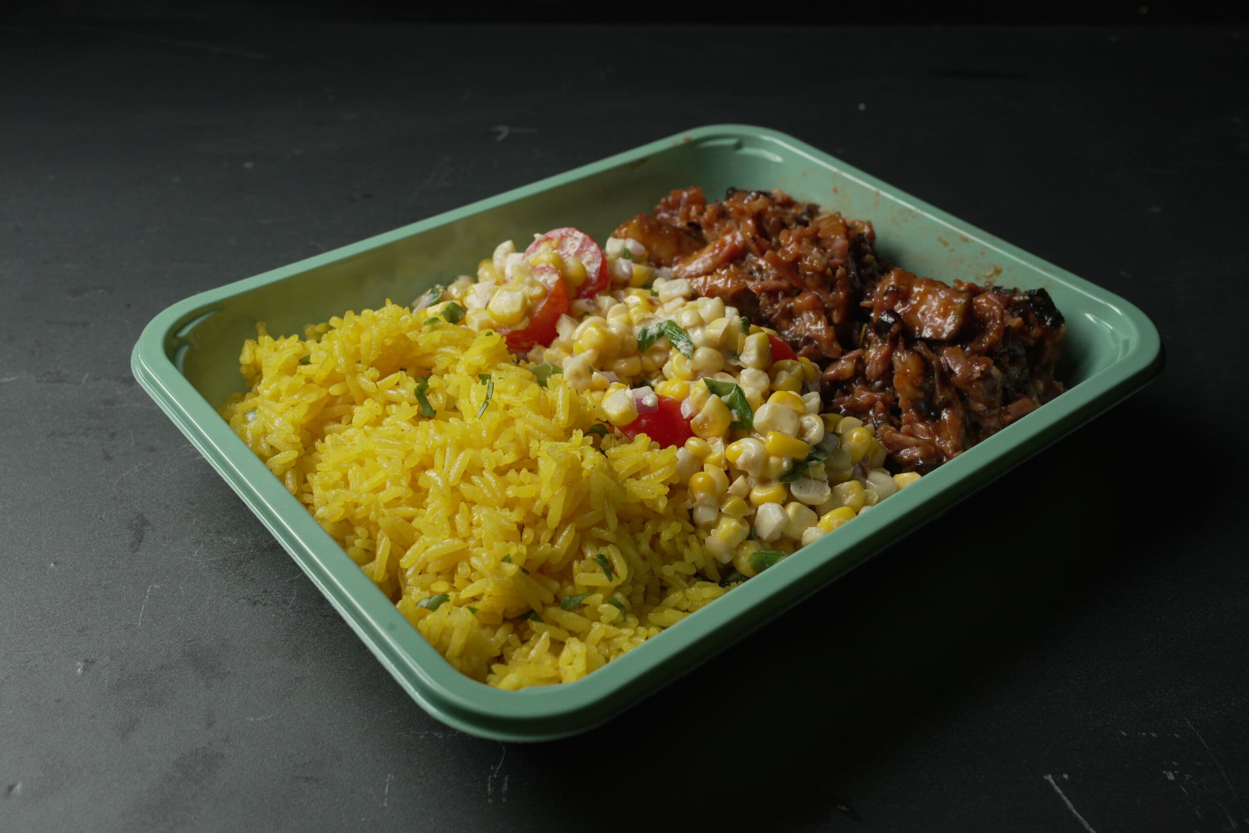 ABLTY performance tray with glazed pulled meat, herb-flecked yellow rice, and a creamy corn and cherry-tomato salad